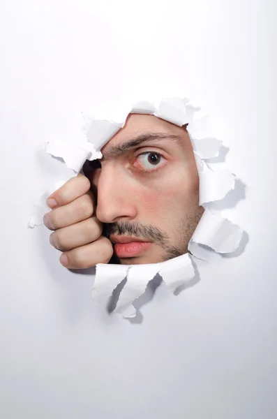 Cara masculina a través del agujero en papel — Foto de Stock