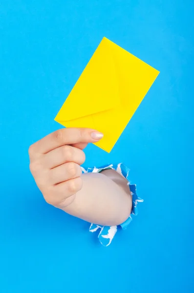 Hand holding paper envelope from hole — Stock Photo, Image