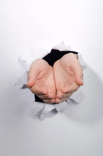 Hands through the hole in paper — Stock Photo, Image
