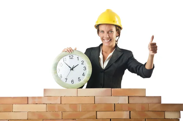 Female builder and clock on white — Stock Photo, Image