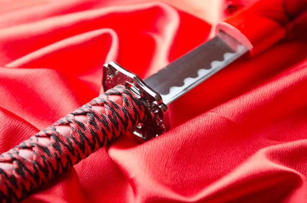 Japanese sword takana on red satin background — Stock Photo, Image