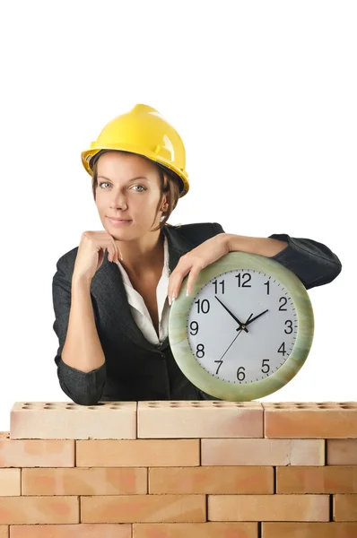 Female builder and clock on white — Stock Photo, Image