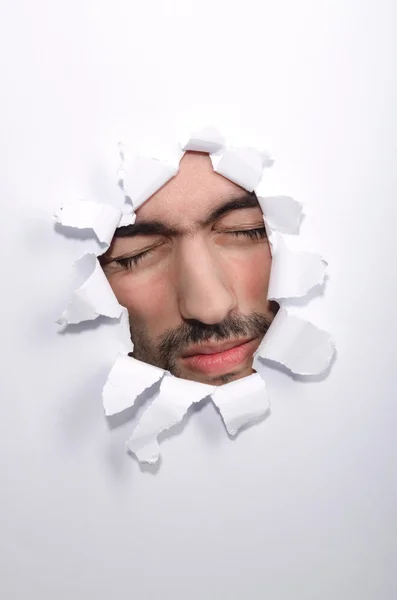 Мужское лицо через отверстие в бумаге — стоковое фото