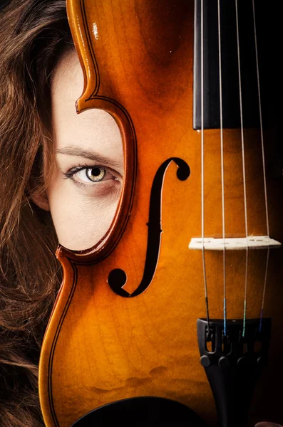 Женщина со скрипкой в темной комнате — стоковое фото
