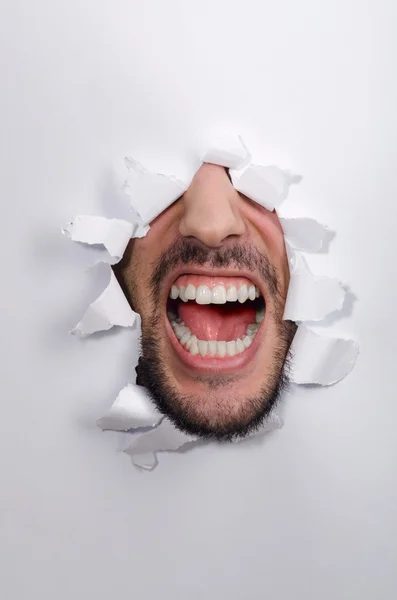 Male face through the hole in paper — Stock Photo, Image