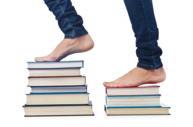 Öğrenci kitap yığınının üzerinde oturuyor