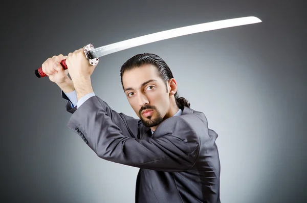 Homem de negócios irritado com espada no quarto escuro — Fotografia de Stock