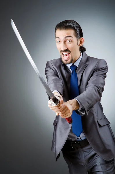 Homem de negócios irritado com espada no quarto escuro — Fotografia de Stock