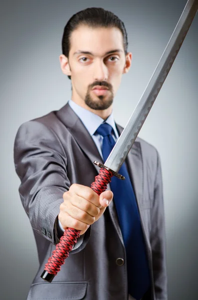 Arg affärsman med svärd i mörkt rum — Stockfoto