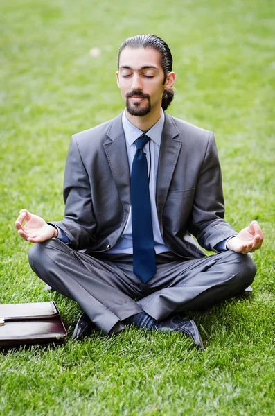 Молодой бизнесмен медитирует в саду — стоковое фото