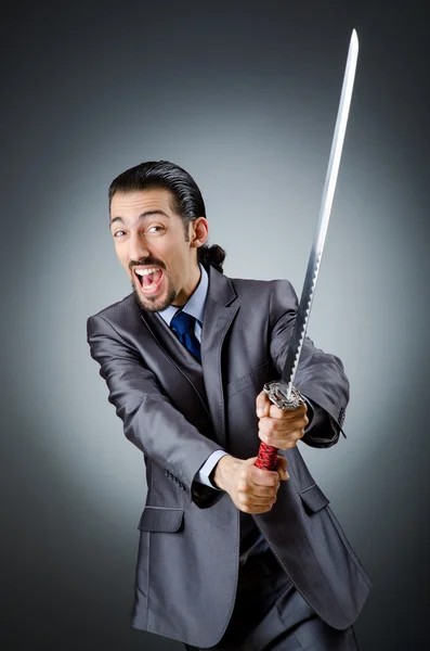 Angry businessman with sword in dark room — Stock Photo, Image