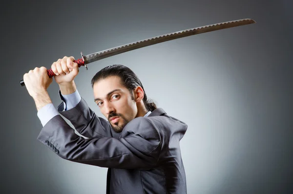 Homem de negócios irritado com espada no quarto escuro — Fotografia de Stock