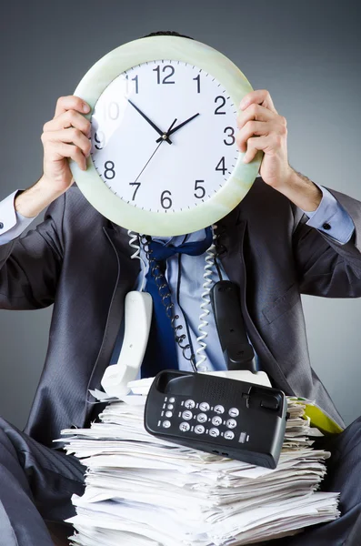 Homme avec horloge et pile de papiers — Photo