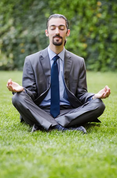 Young businessman meditating in the garden — Stock Photo, Image