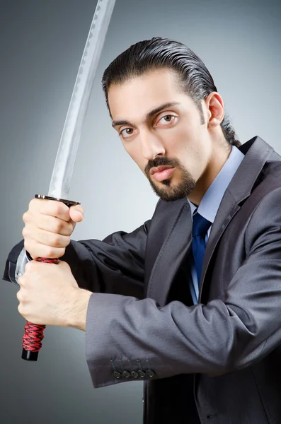 Angry businessman with sword in dark room — Stock Photo, Image