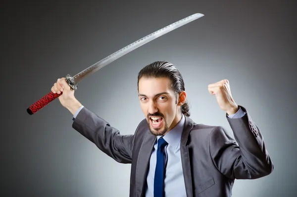 Hombre de negocios enojado con espada en cuarto oscuro —  Fotos de Stock