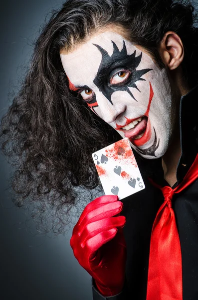 Kwade clown met kaarten in donkere kamer — Stockfoto