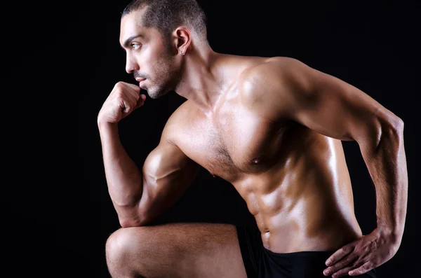 Muscular man in dark studio — Stock Photo, Image