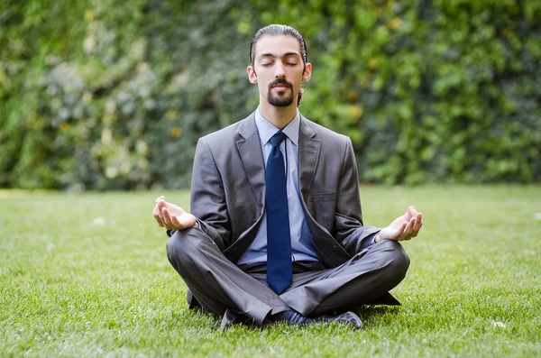 Joven hombre de negocios meditando en el jardín — Foto de Stock