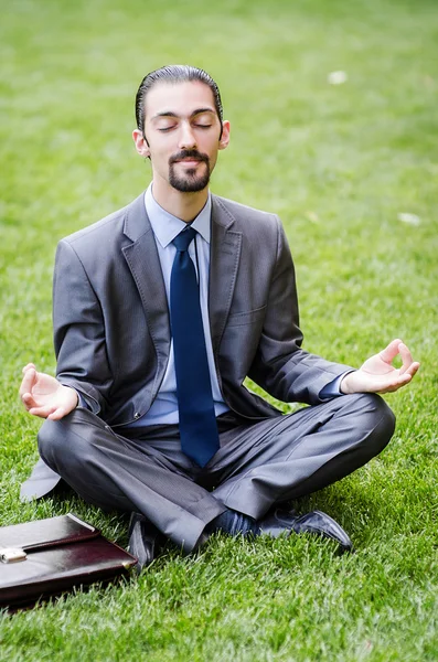 Молодой бизнесмен медитирует в саду — стоковое фото