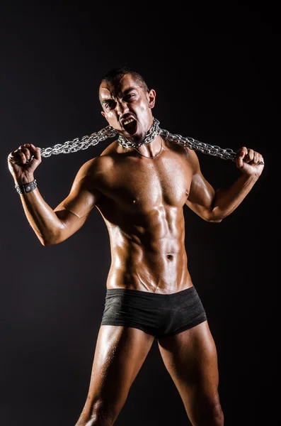 Hombre musculoso con cadena sobre fondo negro — Foto de Stock