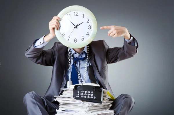 Homme avec horloge et pile de papiers — Photo