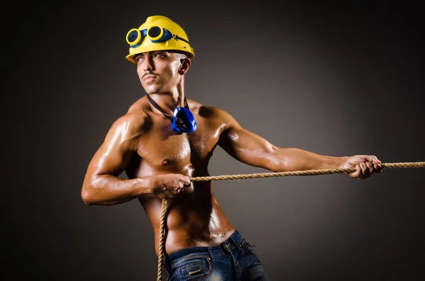 Nude builder pulling rope in darkness — Stock Photo, Image