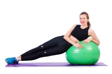 Beyazlar üzerinde top egzersizi yapan genç kadın.