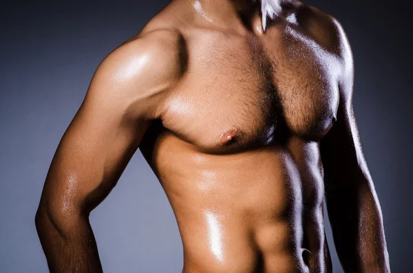 Muscular man in dark studio — Stock Photo, Image