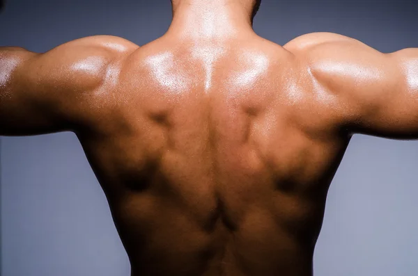 Muscular man in dark studio — Stock Photo, Image