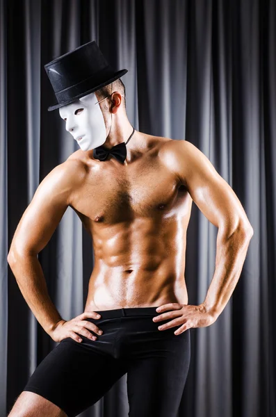 Muscular actor with mask against curtain — Stock Photo, Image