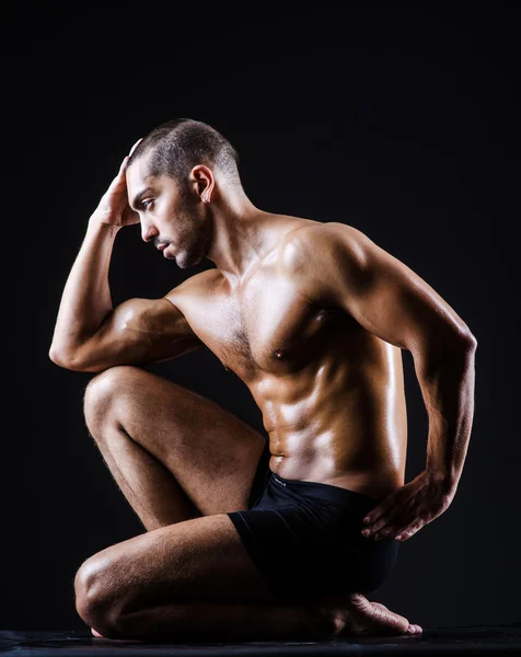 Muskulöser Mann im dunklen Studio — Stockfoto