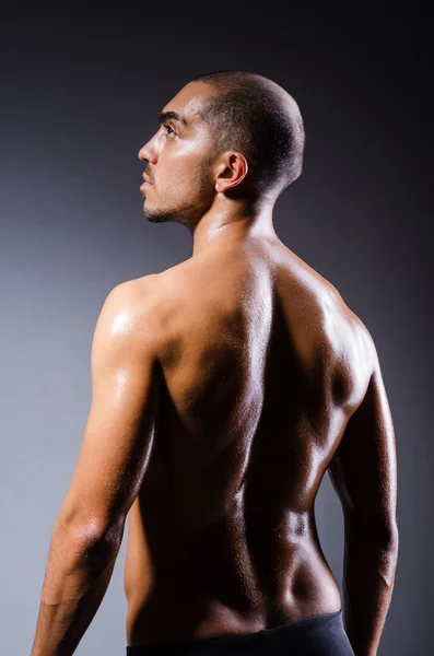 Muscular man in dark studio — Stock Photo, Image