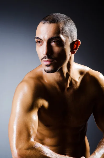 Muscular man in dark studio — Stock Photo, Image