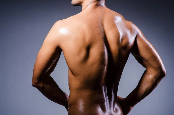 Muskulöser Mann im dunklen Studio lizenzfreie Stockbilder