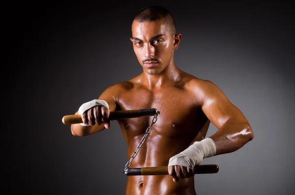 Musculoso hombre con nunchucks en blanco —  Fotos de Stock