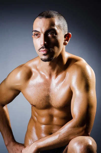 Muscular man in dark studio — Stock Photo, Image