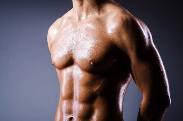 Muscular man in dark studio — Stock Photo, Image