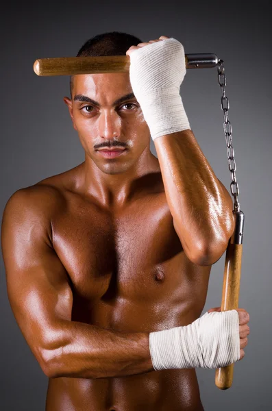 Uomo muscoloso con nunchaku su bianco — Foto Stock