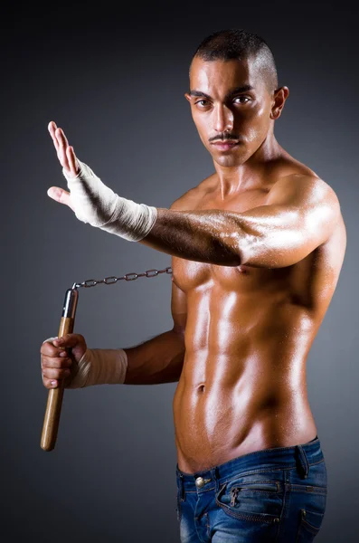 Uomo muscoloso con nunchaku su bianco — Foto Stock