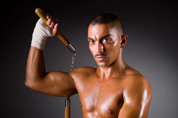 Muscular man with nunchucks on white — Stock Photo, Image