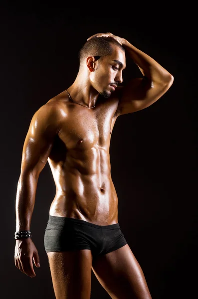 Muskulöser Mann im dunklen Studio — Stockfoto