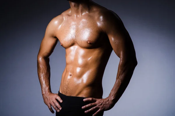 Muscular man in dark studio — Stock Photo, Image