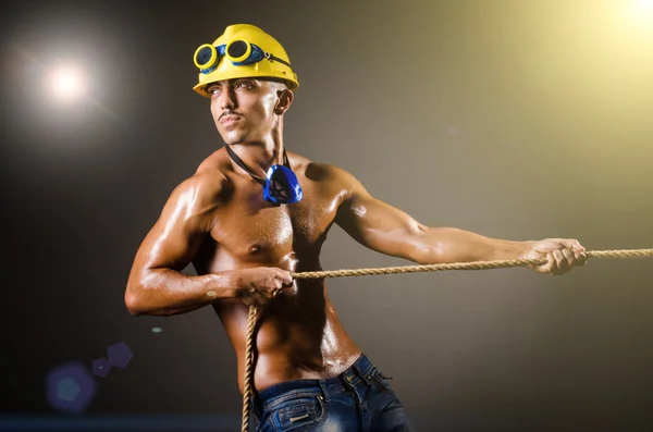 Nude builder pulling rope in darkness — Stock Photo, Image