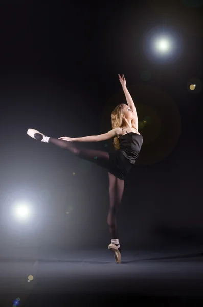 Ballerina dancing in the dark studio — стокове фото