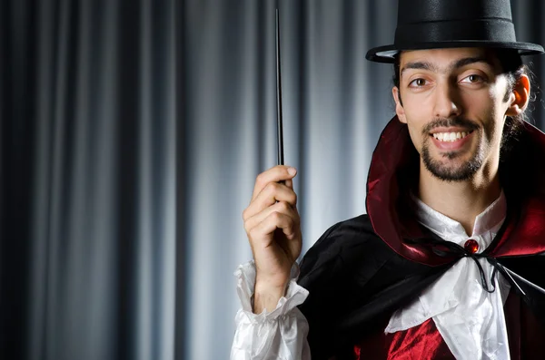 Magician in the dark room with wand — Stock Photo, Image