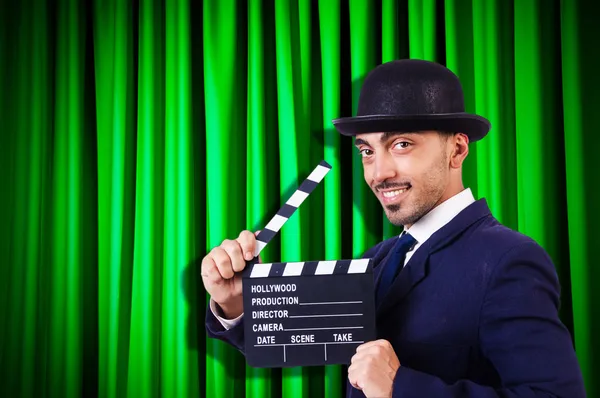 Uomo con film applauso su sfondo tenda — Foto Stock