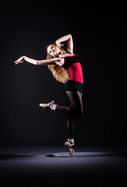 Ballerina dancing in the dark studio — стокове фото