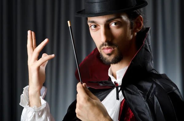 Magician in the dark room with wand — Stock Photo, Image
