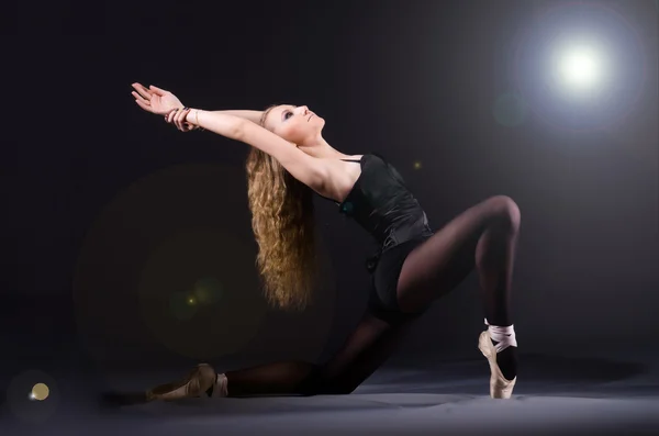 Балерина танцует в темной студии — стоковое фото